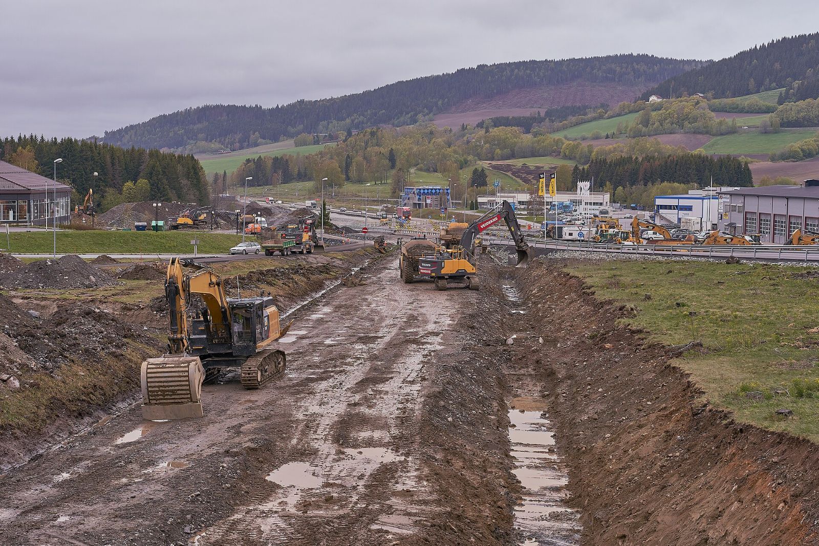 Gravemaskiner og dumpere i arbeid på stort veianlegg