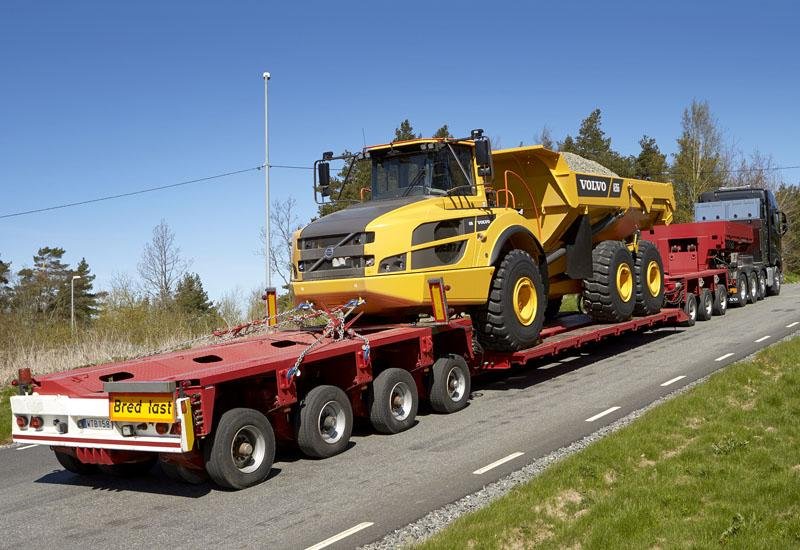 semitrailer med gravemaskin på lasteplanet